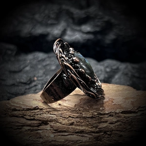 Close-up of handmade wire-wrapped bronze ring with natural labradorite on rustic wood
