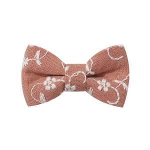 Detail of a handmade cotton bow hair clip with white floral embroidery in dusty rose color