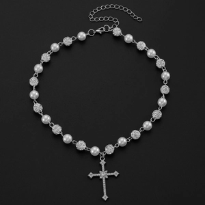 Détail d'un collier croix gothique avec perles blanches et boules de strass brillants