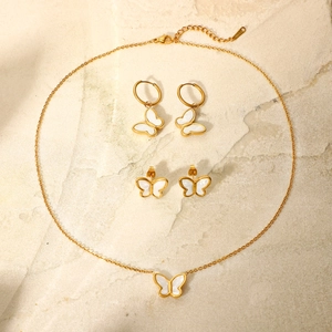Flat lay of gold stainless steel butterfly necklace and earrings set on natural stone