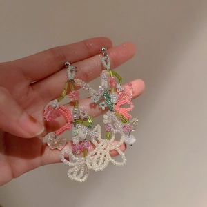 Detail of handmade colorful bead butterfly earrings with floral fringe and silver needles