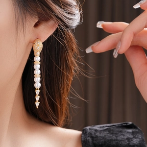 Close-up of elegant gold tassel earrings with white pearls and sparkling zircons