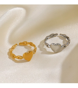 Makro-Detail von 18K Gold- und Silber-Herzringen mit Panzerketten-Muster auf Seide