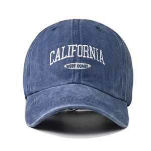 Detailed close-up of white California West Coast embroidery on washed blue baseball cap