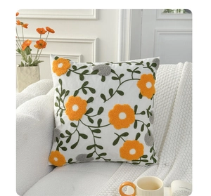 Close-up of yellow and gray floral embroidery detail on a white linen sofa cushion