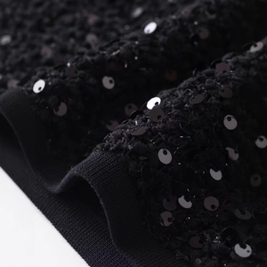 Dettaglio della giacca in maglia con paillettes nere e orlo a costine per consistenza