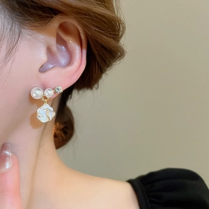 Gros plan d'une boucle d'oreille fleur dorée avec perles portée par un mannequin