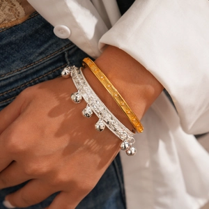 Vue macro de bracelets superposés plaqués or 24 carats et gourmettes à clochettes argent