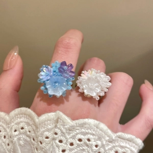 Close-up of colorful resin flower rings with pearlescent finish and beaded details