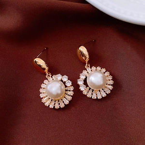Detailed macro view of vintage gold-plated pearl sunflower earrings on red silk background