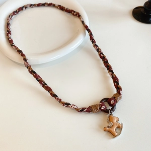 Dettaglio del ciondolo a cavallo a dondolo con tessuto paisley e anello in pelle boho