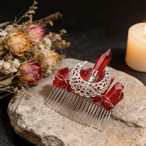 Detail view of handmade moon hair comb with raw red crystals on vintage dark floral background