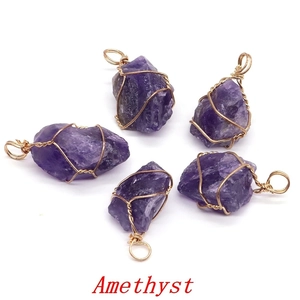 Detailed view of five raw purple amethyst pendants wrapped in gold wire on white background
