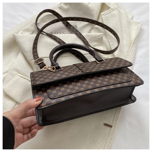 Side view detail of a retro brown litchi pattern handbag with golden hardware
