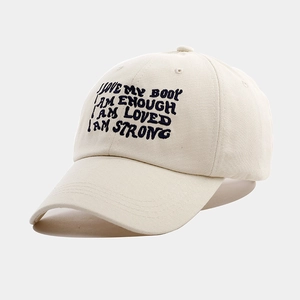 Close-up of embroidered inspirational text on beige cotton canvas baseball cap