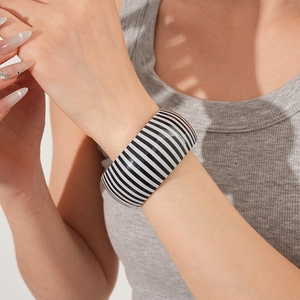 Macro detail of wide striped cuff bracelet with black and white glossy finish on wrist