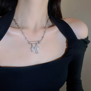 Detail of silver safety pin necklace with double cross pendants worn by a model