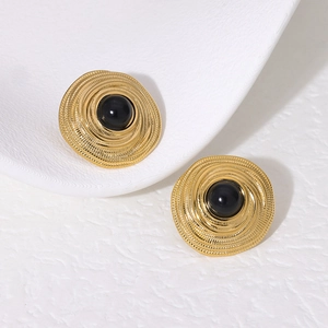 Macro shot of vintage gold spiral earrings with black bead inlay on a white background