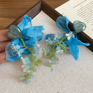 Detail of floral earrings featuring blue chiffon petals and delicate crystal beaded tassels