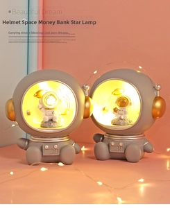 Detailed view of astronaut-themed starry night light and piggy bank in soft warm lighting