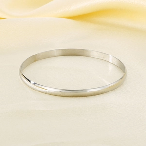 Close-up of polished 5.5mm silver titanium steel bangle on elegant silk fabric