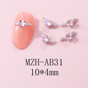 Detail of heart-shaped nail charms with silver wings and colorful purple rhinestone