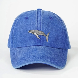 Close-up detail of grey whale embroidery on a dark blue washed denim baseball cap