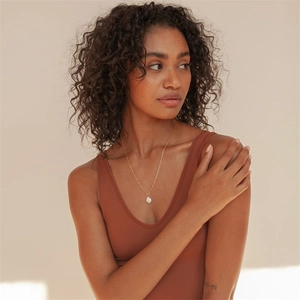 Close-up of elegant gold chain necklace with a baroque pearl pendant on model neck