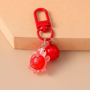 Close-up of a cute red resin turtle keychain with a matching red bell and metal clasp