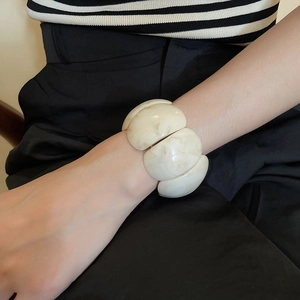 Detail of wide ivory acrylic bracelet with marble texture worn on model wrist