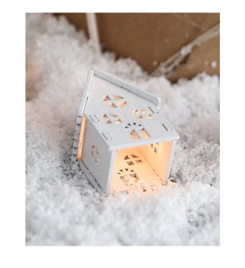 Close-up of a white wooden house LED light buried in snow for Christmas decor