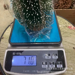 Detailed view of miniature snow-dusted Christmas tree being weighed on a digital scale