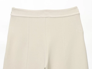 Macro view of high-waisted beige pants showing knit texture and precise topstitching detail