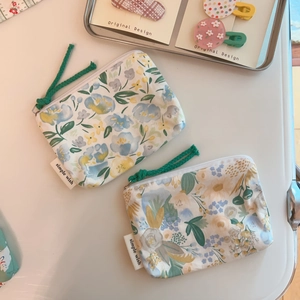 Close-up of floral cotton mini coin purses with green zipper pulls and brand labels