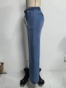 Detail van lichtblauwe wijde jeans met elastische tailleband met koord en zijzakken