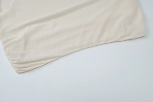 Close-up detail of beige textured fabric showing fine stitching and soft draping