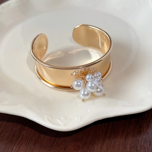 Detailed view of an open golden metal cuff bracelet decorated with white faux pearls