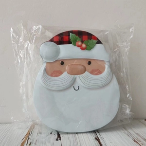 Detailed view of Santa Claus shaped Christmas tin box with red plaid hat on wood surface
