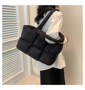 Detail of black quilted puffer tote bag with soft padded shoulder straps for daily commute