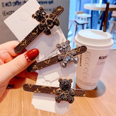 Close-up of rhinestone bear hair clips with monogram patterns on a display card