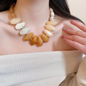 Close-up of irregular acrylic beaded necklace in amber and beige on model's neck