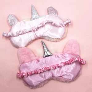 Detail view of pink plush unicorn sleep masks with elastic bands and soft silk lining