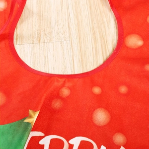 Red Christmas tree skirt with green tree patterns and white Merry text on wooden floor
