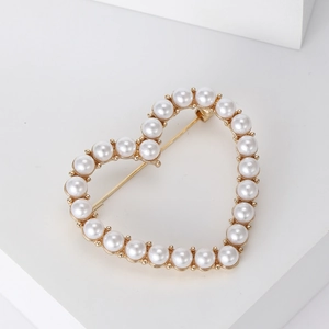 Detailed view of heart-shaped brooch featuring lustrous pearls and golden metal finish