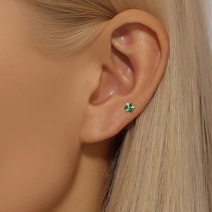 Macro shot of a floral stud earring with green and clear crystals in gold setting