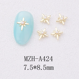 Macro detail of starburst nail charms with pearls on blue nail tips, size 7.5x8.5mm