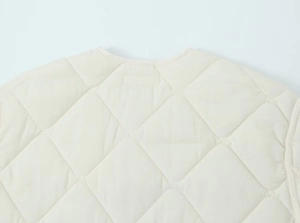 Detail of off-white quilted vest showing crew neck structure and stitching texture