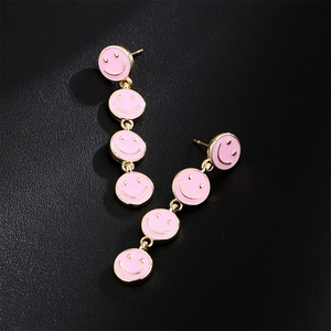 Golden earrings featuring a dangling series of pink enamel smiley face charms