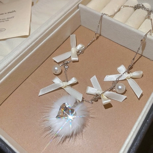 Detailed view of satin bow necklace with faux fur pompom and heart crystal pendant