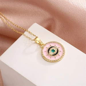 Detailed close-up of a pink enamel Evil Eye pendant with clear crystals on a gold chain